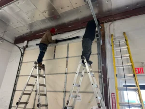 Emergency garage door spring repair in NYC commercial garage by professional technicians on ladders