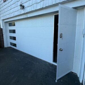 New white garage door installation with side entry door at residential home in Bronx, NY