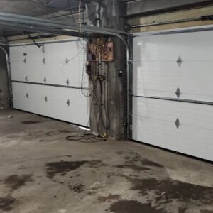 White sectional garage doors installed inside an underground parking garage in Brooklyn, NY