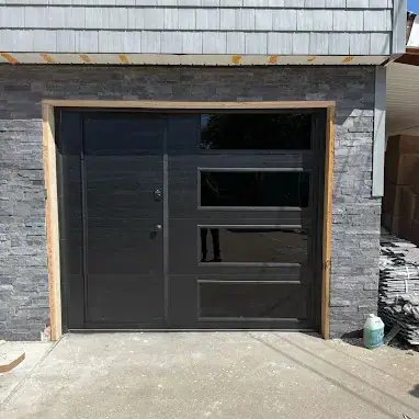 Modern black garage door installation with glass panels in Bronx, NY